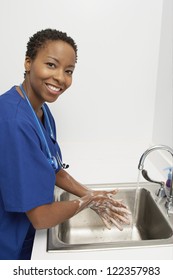 Happy African American doctor washing hands in washbasin