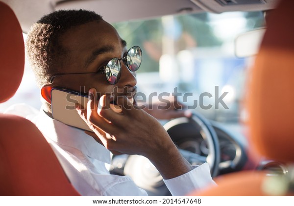 happy african american driving a car with a\
phone, in the summer.