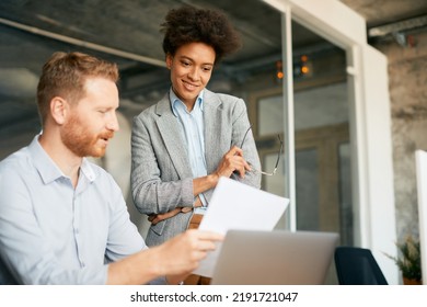 Happy African American executive having a briefing with male colleague in the office.  - Powered by Shutterstock