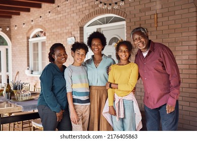 Happy African American Extended Family Gathering For Lunch On A Patio And Looking At Camera.