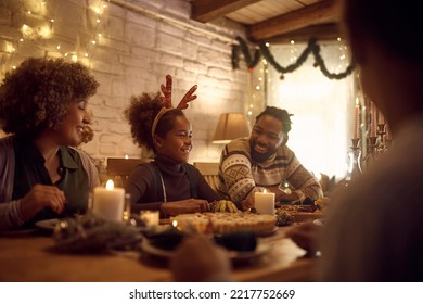 Happy African American Extended Family Enjoying In Conversation While Gathering At Dining Table For Thanksgiving. Focus Is On Girl.