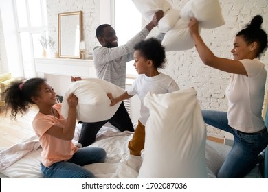 Happy african american family with children pillows fight and laughing. Smiling diverse siblings and parents having fun and playing with cushions in bedroom. - Powered by Shutterstock