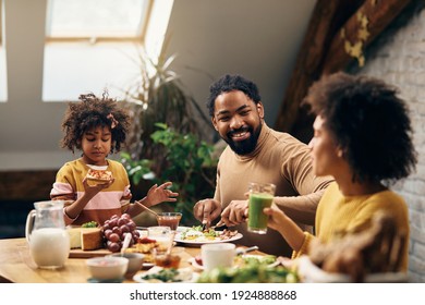 Happy African American Family Communicating During Breakfast At Dining Table.