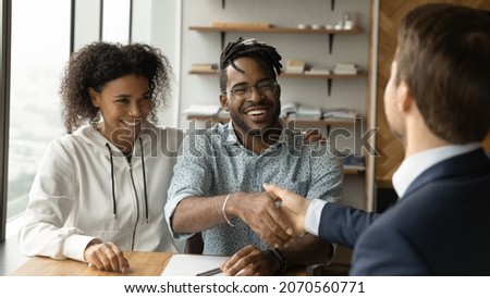 Happy African American family couple shaking hands with professional real estate agent broker lawyer financial advisor, thanking for professional consultation, celebrating making deal in office.