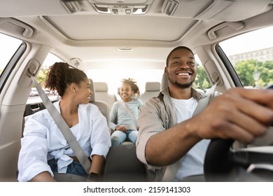 Happy African American Family Driving New Automobile Having Ride In City, Enjoying Road Trip. Parents And Daughter Spending Vacation Traveling By Car. Auto Purchase And Rent. Selective Focus