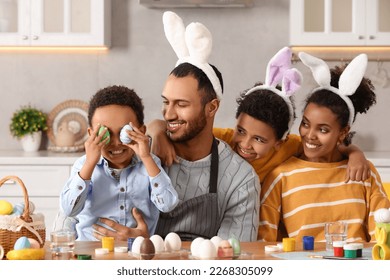 Happy African American family with Easter eggs at table in kitchen - Powered by Shutterstock