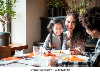 Happy african american family eating lunch together at restaurant and having fun
