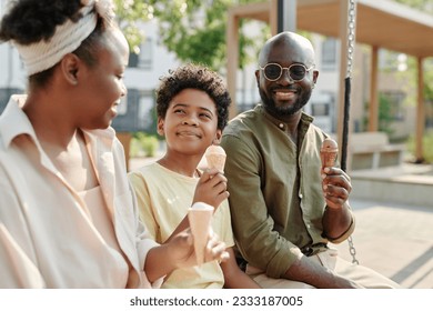 Happy African American family eating ice cream together outdoors while sitting on the swing - Powered by Shutterstock