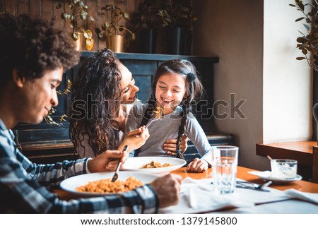 Happy african american family eating lunch together at restaurant and having fun