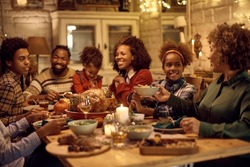 Happy African American Family Enjoying In Lunch While Celebrating Thanksgiving At Dining Table. Focus Is On Girl Passing Food To Her Grandmother.