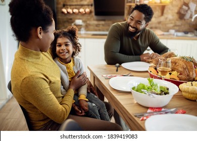 Happy African American family enjoying in Thanksgiving lunch at dining table. Focus is on small girl looking at camera.