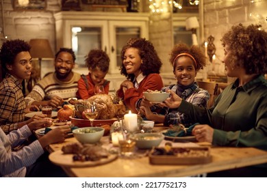 Happy African American family enjoying in lunch while celebrating Thanksgiving at dining table. Focus is on girl passing food to her grandmother. - Powered by Shutterstock