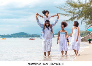 Happy African American family with African American father and asian mother and mixed race kids walking on the beach, thaliand