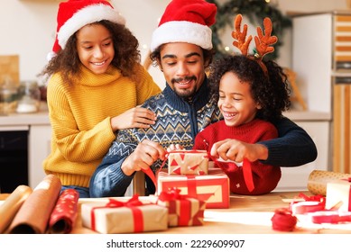 Happy african american family father and kids daughter and son pack Christmas gifts - Powered by Shutterstock