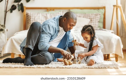 Happy african american family father and baby daughter  playing toys together at home, positive dad  and little kid sitting on floor playing while spending leisure time - Powered by Shutterstock