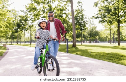 Happy african american family  father teaches boy son  to ride bike in  park   in nature
 - Powered by Shutterstock