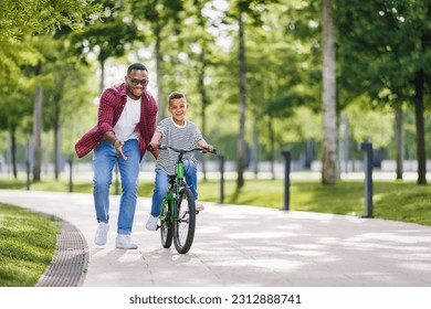 Happy african american family  father teaches boy son  to ride bike in  park   in nature
 - Powered by Shutterstock