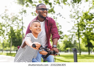 Happy african american family  father teaches boy son  to ride bike in  park   in nature - Powered by Shutterstock