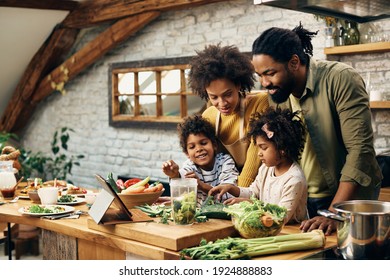 Happy African American family following recipe on touchpad while preparing healthy food in the kitchen. - Powered by Shutterstock