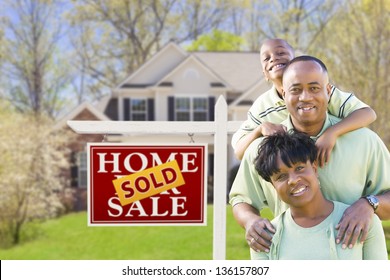 Happy African American Family In Front Of Sold Real Estate Sign And House.