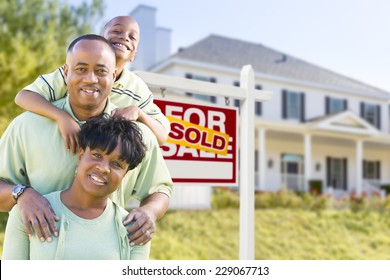 Happy African American Family In Front Of Sold For Sale Real Estate Sign And House.