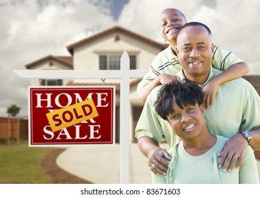 Happy African American Family In Front Of New House And Sold Real Estate Sign.