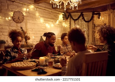 Happy African American Family Having Dinner At Dining Table During Thanksgiving. Focus Is On Man.