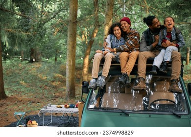 Happy African American family having fun while relaxing on camping van in the forest. - Powered by Shutterstock