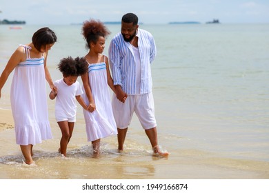 Happy African American Family Holding Hands And Walking Together On The Beach During Holiday.