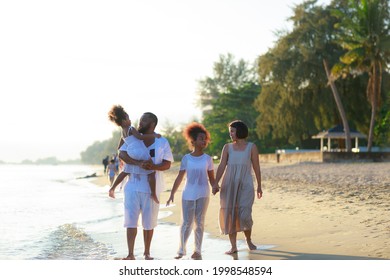 Happy African American Family Holding Hands And Walking Together On The Beach During Holiday.