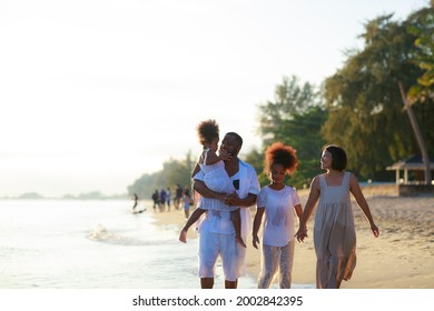 Happy African American Family Holding Hands And Walking Together On The Beach During Holiday.