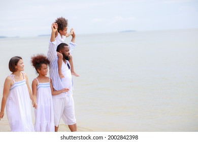 Happy African American Family Holding Hands And Walking Together On The Beach During Holiday.