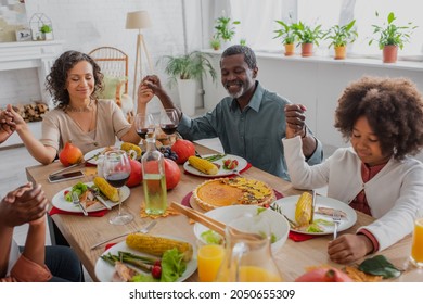 Happy African American Family Holding Hands While Praying Before Thanksgiving Dinner