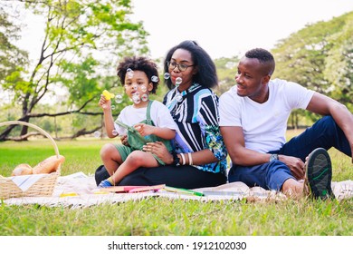 Happy African American family life concept. African American parents (Father, Mother) and little boy enjoying during playing soap bubbles togetherness. family relaxes in green park. Family weekend. - Powered by Shutterstock