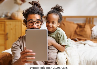 Happy african american family little boy son with young dad watching funny videos on tablet together at home, father with child using computer in bedroom while enjoying weekend - Powered by Shutterstock