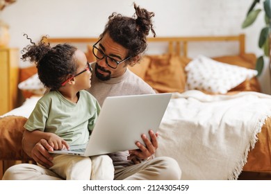 Happy african american family little boy son with young dad watching funny videos on laptop together at home, father with child using computer in bedroom while enjoying weekend - Powered by Shutterstock