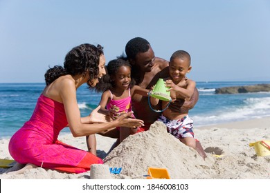 A happy African American family making sandcastle together on a beach.