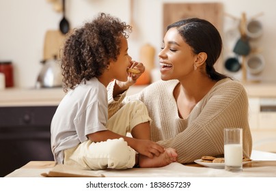 glückliche afrikanische Familie: Mutter und kleiner Sohn essen zu Hause Kekse mit Milch zum Frühstück