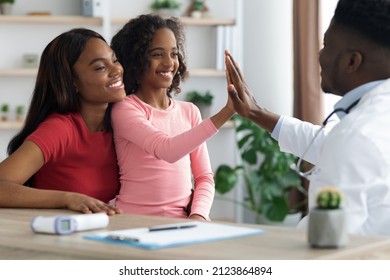Happy African American Family Mother And Daughter Teenager At Appointment With Male Doctor, Healthy Smiling Cute Black Girl Giving Pediatrician High Five, Clinic Interior, Side View