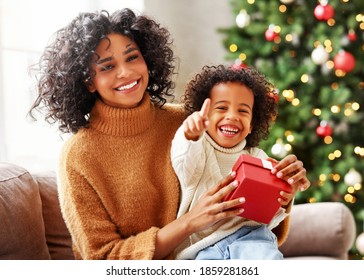 Happy  African American Family On Holiday: Cute Kid Boy And Mother Congratulate Each Other At Christmas Present And Looking At Camera
