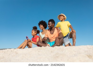 Happy African American Family On Sand At Beach Against Clear Blue Sky With Copy Space. Unaltered, Family, Lifestyle, Togetherness, Enjoyment And Holiday Concept.