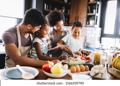 Happy african american family preparing healthy food together in kitchen - Shutterstock ID 1566339790