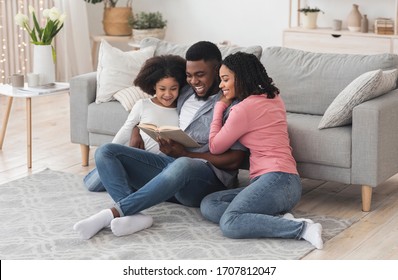 Happy African American Family Reading Book Together, Staying At Home During Coronavirus Quarantine, Sitting On Floor In Living Room, Bonding