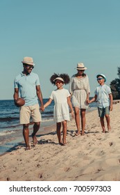 Happy African American Family With Rugby Ball Walking Together On Sandy Beach