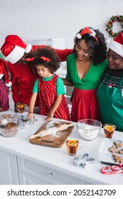 Happy African American Family In Santa Hats Near Girl Preparing Christmas Cookies