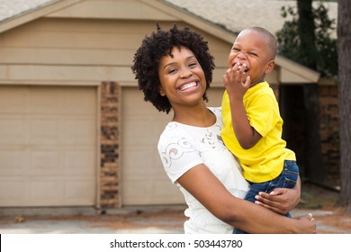 Happy African American Family. Single mom standing in front of her home with her little boy.