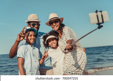 happy african american family taking selfie with smartphone on beach