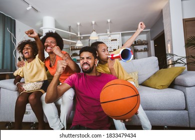 Happy African American Family Of Three Watching Tv And Cheering Basketball Games On Sofa At Home.