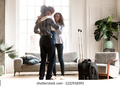 Happy African American family together in living room, loving father holding little preschooler daughter in hands, embracing, smiling attractive wife greeting husband after business trip, journey - Powered by Shutterstock