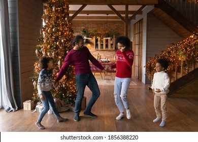 Happy African American Family With Two Adorable Kids Celebrating Christmas, Dancing To Music Near Tree At Home Together, Smiling Mother And Father With Son And Daughter Enjoying Winter Holidays